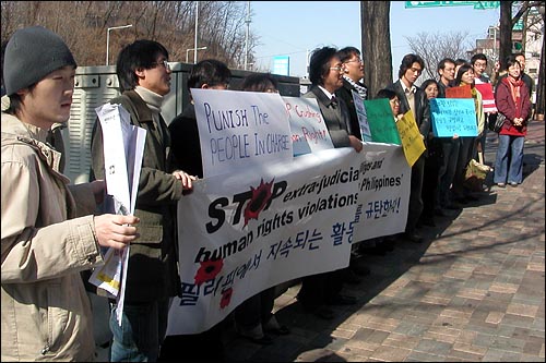 한국의 시민사회단체가 23일 서울 용산 필리핀 대사관 앞에서 "필리핀에서의 비합법적 살인과 인권 탄압을 중지하라"고 외치고 있다. 이들은 '피플파워' 21주년을 앞둔 필리핀에서 무자비한 '정치 살인'이 자행되고 있다고 전했다. 